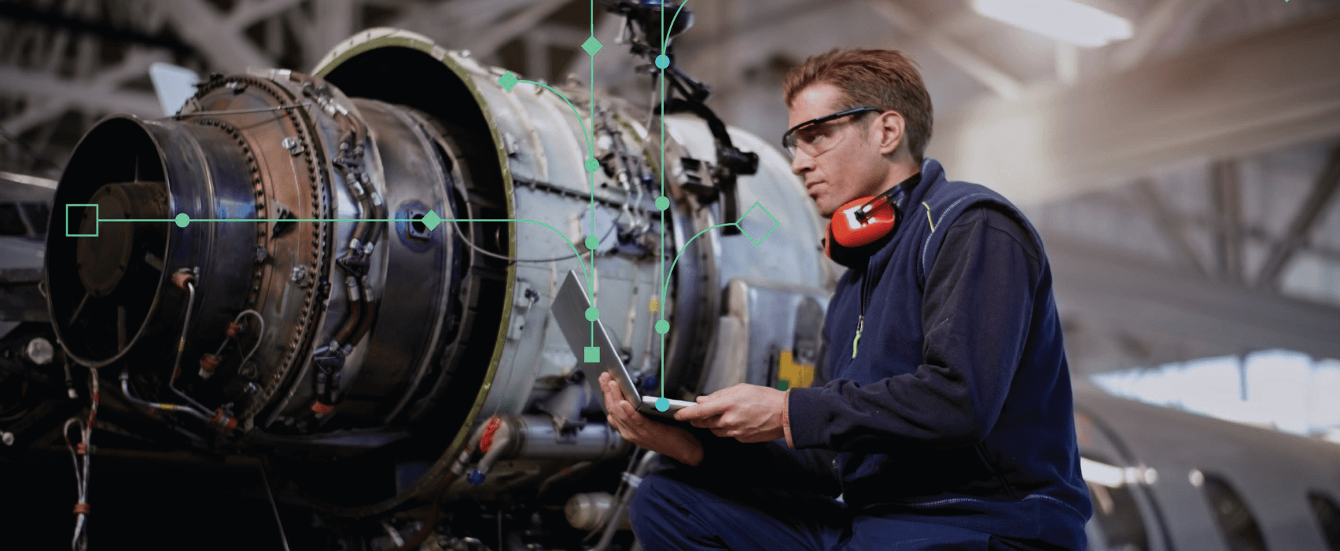 Un tecnico specializzato, equipaggiato con dispositivi di protezione individuale e un tablet, ispeziona attentamente un motore a reazione