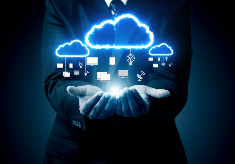 Immagine di un uomo in abito che tiene nelle mani un'icona di cloud computing con diverse icone di dispositivi sospese
