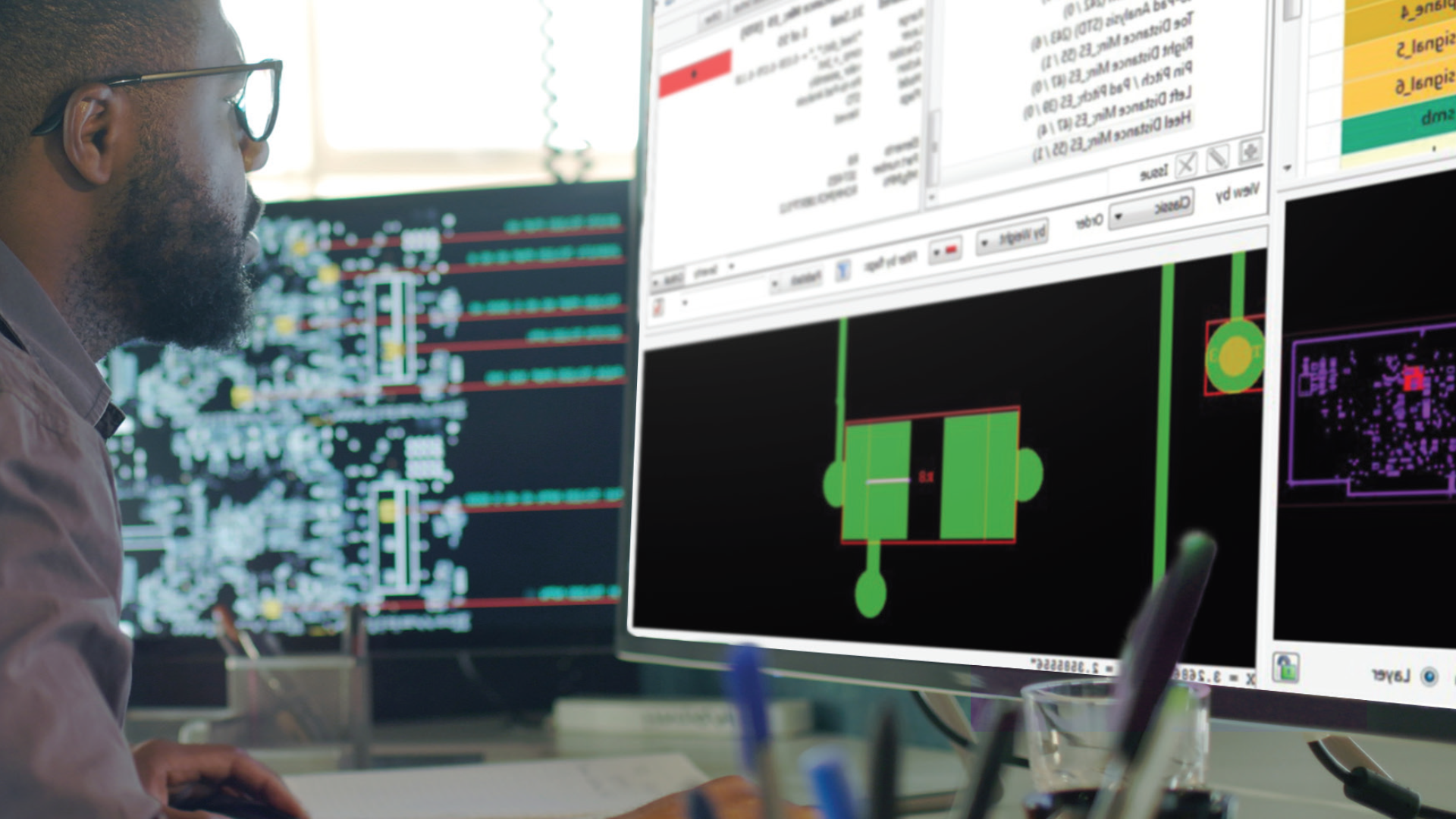 Ingegnere lavora su un progetto su monitor multipli in un ufficio