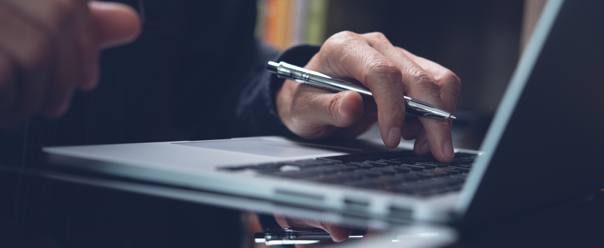 Persona che lavora su laptop con penna in mano