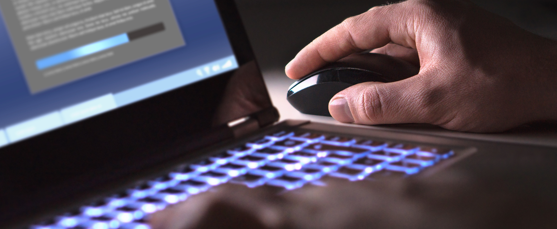 Mano che utilizza un mouse su un computer portatile con tastiera illuminata