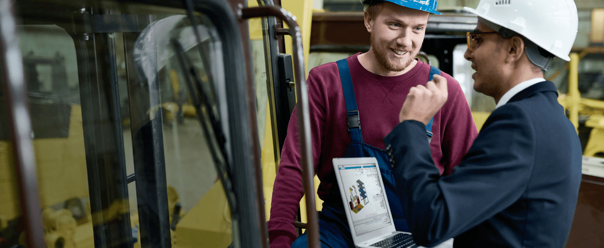 Un professionista mostra ad un tecnico le specifiche di un nuovo macchinario industriale, utilizzando un computer portatile